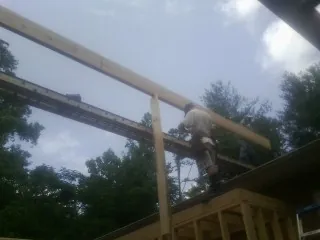 Carpenter setting a ridge beam over a new addition frame — Ice Dam Removal by Roofing Brothers in Prole