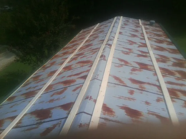 Rusted metal roof panels with new wood purlins before replacement — Storm Damage Roof Repair in Prole by Roofing Brothers