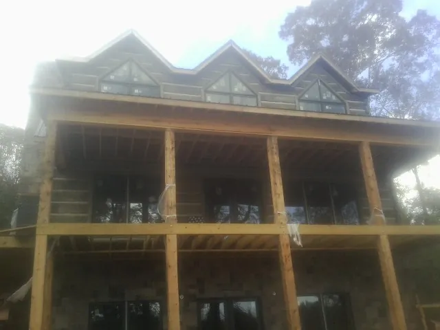 Dormers and porch framing on a large log home under construction — Roof Coating work by our crew in Prole
