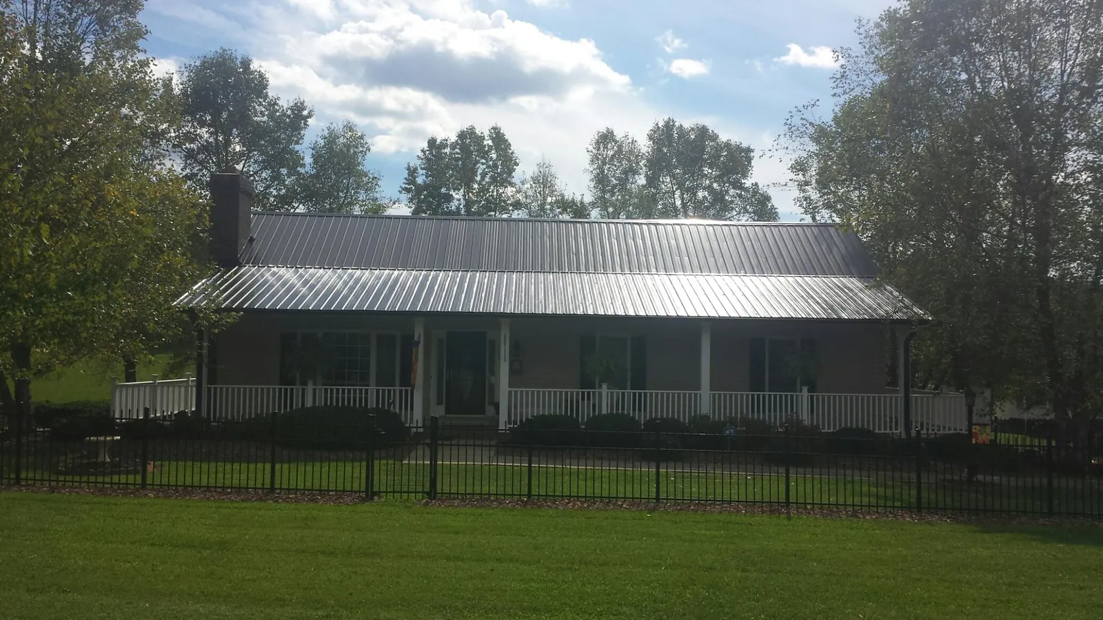 Gray metal roof on a brick ranch with a full width front porch — Gutter Guard Installation work by our crew in Prole