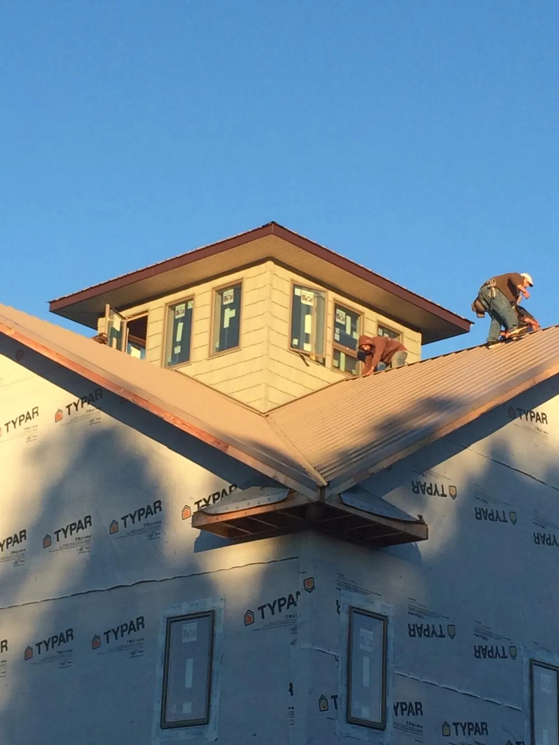 Roofers working around a rooftop cupola on a new metal roof at sunset — Roof Waterproofing in Prole by Roofing Brothers